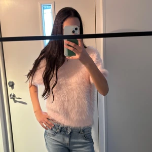 Fluffig rosa tröja Carin Wester  - Supermjuk och fluffig ljusrosa tröja från Carin Wester i storlek S. Tröjan har korta ärmar, rund hals och är stickad med ett lurvigt, pälsliknande material som ger en unik look. Perfekt för dig som vill sticka ut och mysa till det. Har knappt använt och köpte för 500 kr