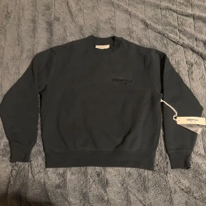 Svart Essentials Fear of God sweatshirt - Svart sweatshirt från Essentials Fear of God med tryck på bröstet och ryggen. Storlek XS men passar S eller M, Klassisk rund hals, ribbade muddar och mjukt material. Om ni har några frågor så är det bara skriva!