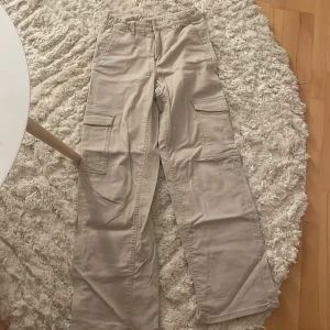 Beiga cargobyxor från Kappahl, stl 164 - Fråga först om de är kvar. Snygga beiga cargobyxor från Kappahl i storlek 164. Byxorna har flera stora fickor på sidorna och raka/ baggiga ben med avslappnad passform. Perfekta för en chill och trendig look. Tillverkade i mjuk bomull för extra komfort.