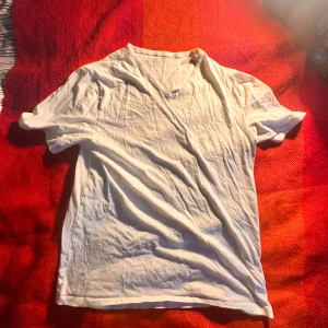 Vit v-ringad t-shirt från Hugo Boss - Vit t-shirt från Hugo Boss med v-ringad hals och broderad logga på bröstet. Klassisk passform och mjukt bomullsmaterial som känns skönt mot huden. Perfekt för dig som gillar stilrena och enkla plagg med diskret branding.