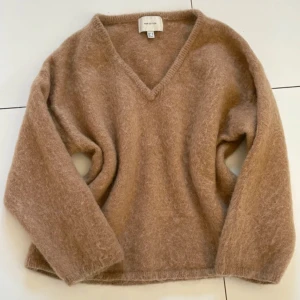 Brun fluffig mohair stickad tröja  - Supermjuk och fluffig beige stickad tröja med v-ringning och lång ärm. Tröjan har en loose fit och är perfekt för lager-på-lager under kyliga dagar. 