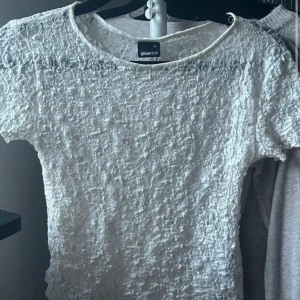 Vit spetsblus från Gina Tricot XS - Säljer en söt vit blus från Gina Tricot i storlek XS. Toppen är helt täckt av spets med blommigt mönster och har korta ärmar. Rund halsringning och lätt transparent material.