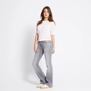 Ljusrosa stickad blus med kort ärm - Supersöt ljusrosa stickad blus med kort ärm och rund hals. Blusen har ett genombrutet, virkat mönster som ger en luftig känsla och ribbade muddar vid ärmslut och nederkant. Perfekt för dig som gillar en feminin och trendig look.