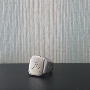 Louis Vuitton silverring - Snygg och chunky silverring från Louis Vuitton med LV-logga ingraverad på framsidan och en ikonisk blomdetalj på sidan. Ringen har en fyrkantig platta och stilren design som ger en lyxig vibe.