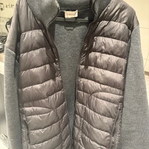 Grå pufferjacka från Moncler - Snygg grå cardigan från Moncler. Skick 10/10 inga skador eller liknande storlek XL men passar M/L också. Skriv privat för mer frågor.