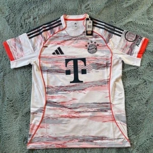 Bayern München bortatröja Adidas XL - Säljer en FC Bayern München bortatröja från Adidas i storlek XL. Tröjan är vit med röda och gråa grafiska mönster, har korta ärmar och klassiska Adidas-ränder på axlarna. Materialet är lätt och andas, perfekt för fotboll eller träning. Slim fit-modell.