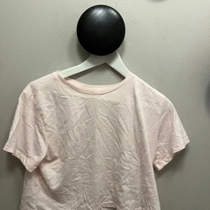 Ljusrosa croppad t-shirt - Enkel och stilren ljusrosa t-shirt med croppad passform och korta ärmar. T-shirten har rund halsringning och är tillverkad i mjuk bomull, perfekt för en avslappnad look.