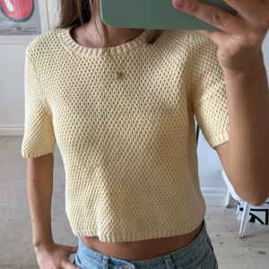 Ljusgul stickad tröja från COS - Superfin ljusgul stickad tröja från COS med kort ärm och rund hals. Tröjan har en boxig, lite croppad passform och är gjord i ett grovt stickat bomullsmaterial.