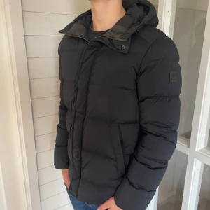 J. Lindeberg dunjacka - En riktigt snygg vinter dunjacka från J.Lindeberg i mycket bra skick, den är i storlek M och jag på bilderna är 184 cm och väger 82 kg, det finns ett litet hål på insidan av jackan (skriv för bild) tveka inte att höra av er vid funderingar