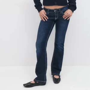 Mörkblå bootcut jeans med fickor  - Snygga mörkblå jeans med bootcut passform och tydliga vita kontrastsömmar från Gina Young. Byxorna har låg midja och coola detaljer på bakfickorna. Jätteskönt material och dom är helt slutsålda. Nypris: 300kr 