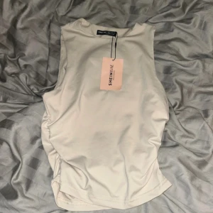 Beige ärmlös linnetopp från SHEIN - Snygg beige ärmlös linnetopp från Shein med rund halsringning. Toppen har en clean och enkel design, perfekt att matcha med jeans eller kjol. Tillverkad i mjukt och stretchigt material för en bekväm passform.