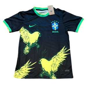 Brasilien Nike fotbollströja svart/gul - Snygg svart Brasilien fotbollströja från Nike med gula och gröna detaljer. Tröjan har korta ärmar, rund hals och stora gula fåglar tryckta på framsidan. Broderat CBF-märke på bröstet och gröna/gula muddar. Tillverkad i lätt och ventilerande material.