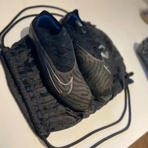 Nike phantom - Hej! Jag säljer dessa Nike Phantom som har varit några av de bästa fotbollsskor jag ägt, men nu vill jag bara bli av med dem. Skorna är slitna och har gått sönder framtill, både på ovansidan och undersidan. Sulorna saknas, men dobbarna är fortfarande i bra skick. De går fortfarande att använda om man tejpar eller limmar ihop undersidan.