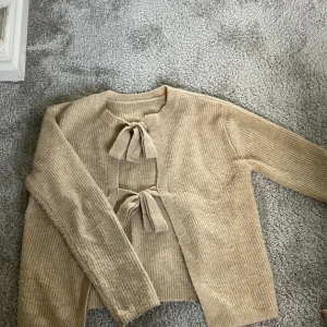 Beige stickad kofta med knyt - Superfin beige stickad kofta med två knyt framtill. Koftan har lång ärm och ribbad struktur❤️