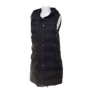 Svart lång dunväst med huva - Säljer en svart lång dunväst med huva och dragkedja samt tryckknappar framtill. Västen har quiltad design och två sidofickor med dragkedja. Perfekt för lager-på-lager och chill stil under kyliga dagar. Ordinarie pris:600