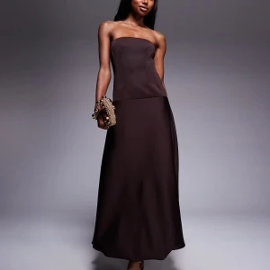 Mörkbrun axelbandslös långklänning - Supersnygg mörkbrun axelbandslös långklänning med figurnära överdel och lätt utsvängd kjol. Klänningen har en stilren och minimalistisk design i ett slätt, elegant tyg som ger en lyxig känsla. För fler frågor och bilder, hör av dig!