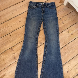 Blå bootcut jeans med slitningar - Snygga blå jeans med bootcut-modell och lätt slitna detaljer framtill. Klassisk femficksdesign och normal midja. Jeansen har en cool tvättad look och är tillverkade i mjukt denimtyg som sitter skönt hela dagen.
