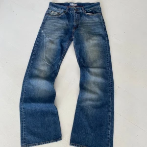 Tommy Hilfiger Manhattan jeans blå 30/32 - Blå jeans från Tommy Hilfiger, modell Manhattan, med klassisk femficksdesign och extra ficka på benet. Snygga slitningar och kontrastsömmar, Hilfiger-logga på ficka och bakre läderpatch. Raka ben och normal passform. Perfekta för en avslappnad streetstil. Kan säljas på flera plattformar, meddelas vid köp