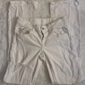 Vita jeansbyxor från Gina Tricot - Snygga vita jeansbyxor från Gina Tricot i storlek 164. Modellen har raka ben, slitna detaljer vid knäna och klassiska fickor både fram och bak med silverfärgade knappar. Perfekta för dig som gillar en fräsch och trendig look. 