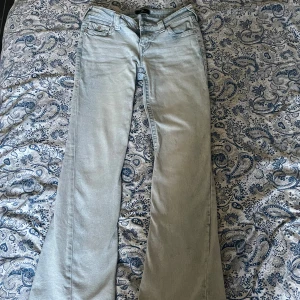 Ljusblå bootcut jeans från True Religion - Säljer ett par ljusblå jeans från True Religion med bootcut-modell och låg midja. Jeansen har klassiska fickor med snygga detaljer och broderier bak samt en ikonisk patch på linningen. Tillverkade i jeansmaterial med en riktigt fräsch tvätt. Säljer dessa pågrund av att de är för stora. Det står att de är w26, men känns större. S/M