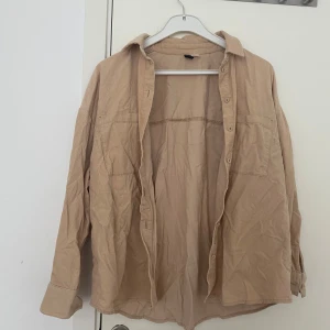 Beige oversize  - Säljer en beige overshirt i mjuk manchester med klassisk krage och knäppning framtill. Skjortan har två bröstfickor och långa ärmar med manschett. Perfekt att slänga över en t-shirt en sen sommar kväll.