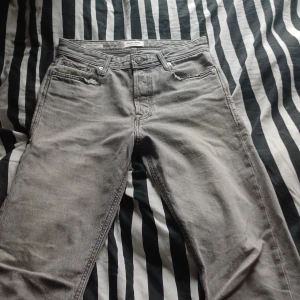 Grå loose fit jeans Jack & Jones - Säljer ett par grå jeans från Jack & Jones i loose fit-modell, modellen heter Chris. Jeansen har klassisk femficksdesign, raka ben och är tillverkade i jeanstyg. Perfekta för dig som gillar en avslappnad och trendig stil.