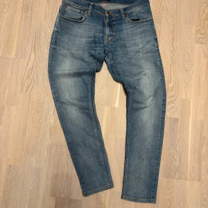 Ljusblåa jeans från Nudie jeans, stolek 36 - Säljer mina tvärfeta nudie jeans i ljusblått, dem har fått en riktigt fet tvätt. Finns inga skavanker på dem. Storlek W36, dem är 107 cm långa, midjemåttet är 46cm, benöppningen är 17cm och låtvidden är 28cm