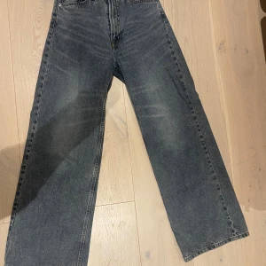 Wide jeans från H&M Divided, grå - Säljer ett par gråa wide jeans från H&M Divided i storlek 36. Byxorna har en rak och bred passform med klassisk femficksdesign och dragkedja. Perfekta för dig som gillar en avslappnad stil och vill ha jeans med lite extra utrymme.