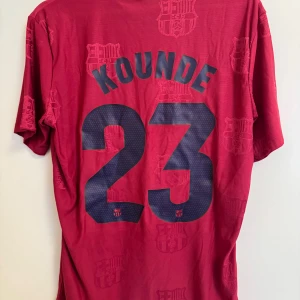 FC Barcelona Koundé 23 matchtröja Nike - Säljer en unik FC Barcelona fotbollströja med Koundé och nummer 23 på ryggen. Tröjan är röd med mörkblå detaljer, klubbmärke på bröstet och Spotify-logga. Tillverkad i lätt funktionsmaterial, perfekt för match eller träning.