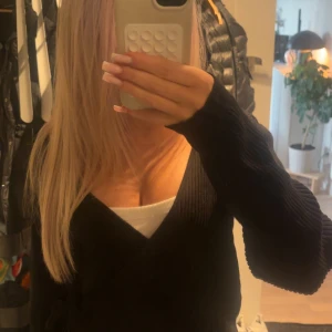 Svart omlottkofta från Vila, S - Svart ribbad omlottkofta från Vila i storlek S. Koftan har långa ärmar, knyt i midjan och croppad passform. Materialet är mjukt och stickat, perfekt för lager-på-lager. Snygg att matcha med jeans eller kjol för en trendig look.