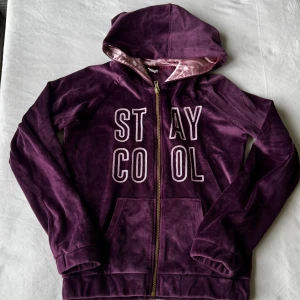 Mörklila zip-up - Mörklila zip hoodie i velour från Uniq Young med texten ’STAY COOL’, i storlek 146/152. Fraktar inom 24h!