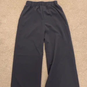 Blåa och gröna wide byxor - Två par byxor i blått och mörkgrönt, båda med breda ben och elastisk midja för skön passform. Perfekta för en chill och avslappnad stil. Materialet känns mjukt och lätt, vilket gör dem bekväma att bära hela dagen. 