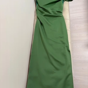 Grön långklänning asos design - Säljer en stilren grön långklänning med enkel design. Klänningen är sydd i ett mjukt polyestertyg som faller snyggt längs kroppen. Perfekt för dig som gillar minimalistisk stil och vill ha en klänning med clean look.