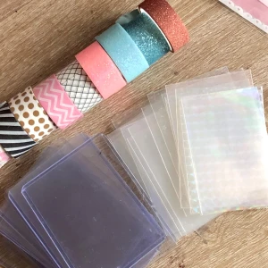 Toploaders, plastfickor & washitejp set - Paket med flera toploaders och plastfickor några genomskinliga några holografiska samt 8 rullar dekorativ washitejp i olika färger och mönster. Perfekt för pyssel, scrapbooking eller att skydda samlarkort. Typ alla toploaders har lite repor och klister från tejp som går att ta bort men är i gott bruksskick!<3