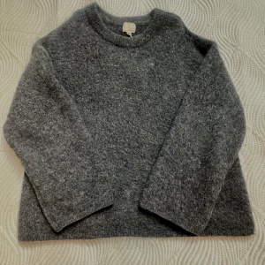 Grå stickad tröja från H&M - Mysig grå stickad tröja från H&M i mohair- och ullblandning. Tröjan har en enkel, rak passform med rund hals och långa ärmar. 