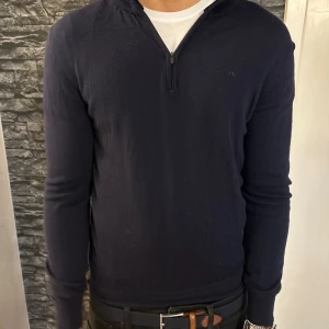 Mörkblå half zip tröja J.Lindeberg - Snygg mörkblå långärmad tröja från J.Lindeberg med half zip-dragkedja vid halsen. Tröjan är stickad i mjukt material och har en stilren look med diskret logga på bröstet. Perfekt för lager-på-lager. Nypris : 1500kr