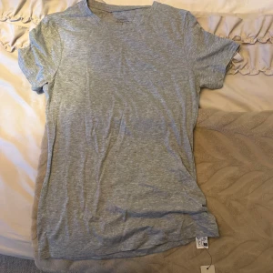 Grå basic t-shirt från Intimissimi - Enkel och stilren grå t-shirt från Intimissimi i 100% ultrafräsch bomull. Modellen är klassisk med rund hals och korta ärmar, perfekt för en clean och avslappnad look. T-shirten har en mjuk känsla och passar till allt.