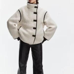Vit teddyjacka hm - Säljer en fluffig vit teddyjacka med svarta kontrastsömmar och knappar framtill. Jackan har hög krage, långärmade och loose passform 