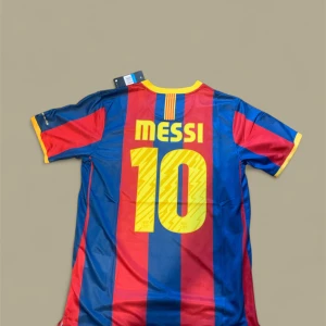 Barcelona 10/11 fotbollströja Messi - Säljer en autentisk FC Barcelona fotbollströja från Nike med Messi och nummer 10 på ryggen. Tröjan har klassiska blå och röda vertikala ränder, gula detaljer och klubbmärke på bröstet. Tillverkad i lätt, ventilerande Dri-FIT polyester. Perfekt för dig som älskar Barca och Messi.