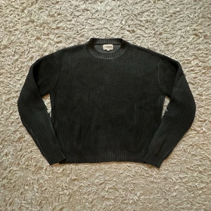 Ktwo Studios Los Angeles Ribbstickad Tröja  - Helt ny och oanvänd, med etiketter kvar. Detta är ett riktigt statement-plagg för den som vet. En extremt högkvalitativ och mjuk ribbstickad tröja från det exklusiva streetwear-märket Ktwo Studios från Los Angeles. Plagget är känt för sin tunga, lyxiga kvalitet och perfekta passform, vilket gör det till en ultimat vintertröja. Den mörkgrå (nästan svarta) färgen är otroligt mångsidig och utstrålar en minimalistisk, exklusiv look. 