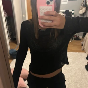 Svart långärmad topp från Nelly - Säljer en svart, tunn och lätt transparent långärmad topp från Nelly. Modellen är slim och har en enkel rund halsringning. Materialet är mjukt och stretchigt