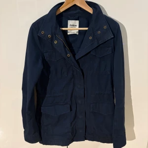 Blå Felid jacket xs( SITTER SOM S) - Felid jacket i mörkblå färg från Dobber, storlek XS. Jackan har fyra stora fickor framtill, metallknappar och dragkedja. Klassisk krage och justerbar midja. Perfekt för dig som gillar stilren och funktionell design. OBS SITTER SOM S, mvh Charlie 🤝