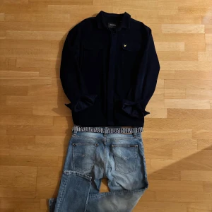 Mörkblå manchester overshirt Lyle & Scott L - Snygg mörkblå overshirt från Lyle & Scott i mjuk manchester. Klassisk krage, två bröstfickor med lock och ikonisk gul logga på ena fickan. Perfekt lager-på-lager-plagg med avslappnad passform och stilren look. Priser kan diskuteras och om du har några funderingar är det bara att höra av sig🫡