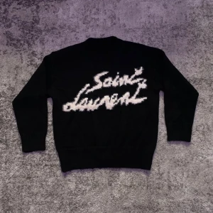 Svart Saint Laurent tröja  - Väldigt fin Saint Laurent tröja i nytt skick, svart med vit text i storlek S. Stilren och perfekt för kyligare dagar pga tröjans varma material. Hör gärna av dig vid minsta fundering om mått, pris eller annat!