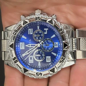 Blå och silverfärgad klocka Geneva - Stilren klocka från Geneva med blå urtavla och silverfärgat armband i metall. Klockan har flera små urtavlor, markerade siffror och detaljerad boett. Perfekt accessoar för dig som gillar en sportig och modern look.