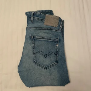 Replay Grover ljusblå jeans, stl 32 - Snygga ljusblå Replay Grover jeans med klassisk femficksdesign och coola detaljer på bakfickorna. Jeansen har en rak passform och är tillverkade i mjukt denimtyg som sitter skönt hela dagen. Perfekt för dig som gillar stilrena och moderna jeans.