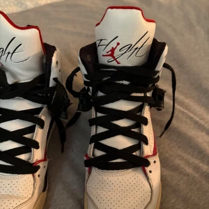 Nike Air Jordan 4 Retro vit/röd/svart - Nike Air Jordan 4 Retro sneakers i vit, röd och svart. Höga med snörning, perforerad ovandel och klassisk Jumpman-logga på hälen. Skorna har platt sula och detaljer i skinn och syntet. Perfekt för dig som gillar streetstyle och ikoniska basketskor.Står storlek 39 men passar 37 och 38 också 