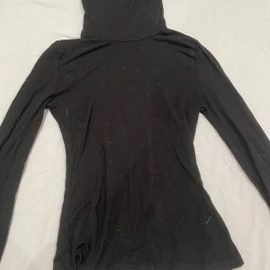 Svart långärmad turtleneck  - Svart tröja med långärmade smala ärmar. Tröjan har en enkel, slim passform. Perfekt för dig som gillar minimalistisk stil och vill ha något bekvämt att dra på dig.