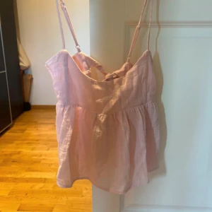 Ljusrosa linnetopp med rosett - Supersöt ljusrosa linnetopp med justerbara smala axelband och en stor rosett i ryggen. Toppen är i linne material 😇