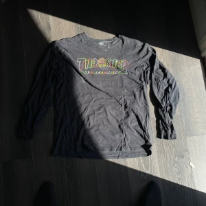 Svart Thrasher långärmad tröja - Svart långärmad tröja från Thrasher med färgglatt tryck på bröstet där det står 'Thrasher San Francisco'. Skön passform och perfekt för dig som gillar streetwear. Klassisk crewneck och mjukt bomullsmaterial.